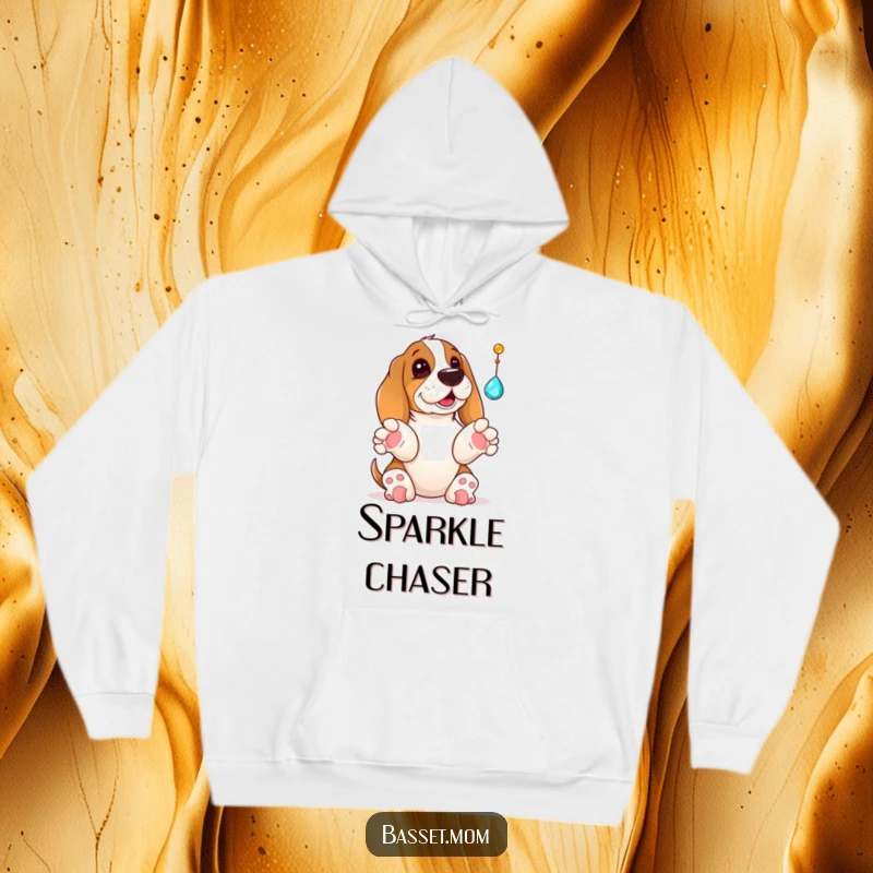 Funny Basset Hound hoodie featuring a dog with its paws up, playfully batting at a dangling jewel, looking utterly captivated and delighted.