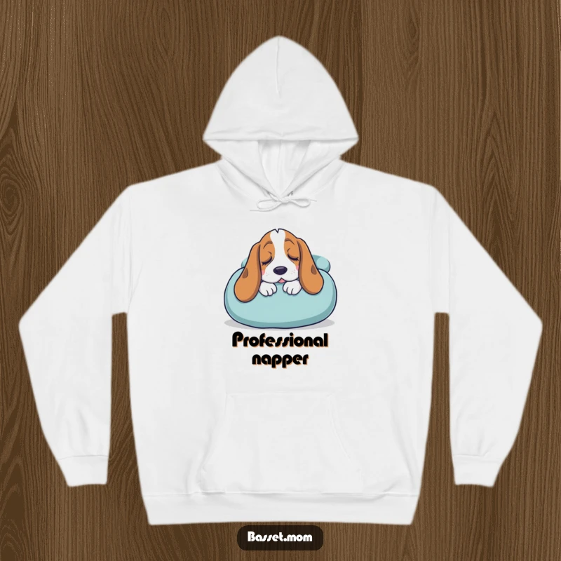Funny Basset Hound hoodie depicting a sleepy dog snuggling into a giant cushion, offering ultimate cozy humor and comfort.