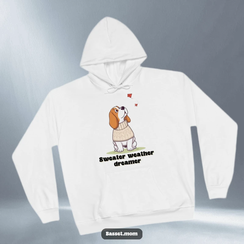 Funny Basset Hound hoodie depicting a dog in a knitted sweater looking up at a kite, offering cozy humor and whimsical charm.