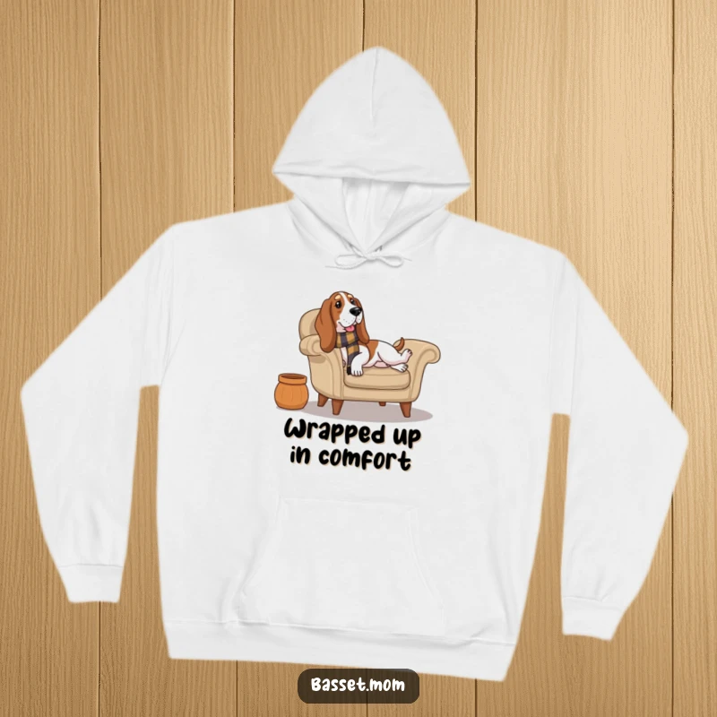 Funny Basset Hound wearing a scarf lounges on a cozy armchair, bringing ultimate comfort and humorous relaxation to this warm hoodie.