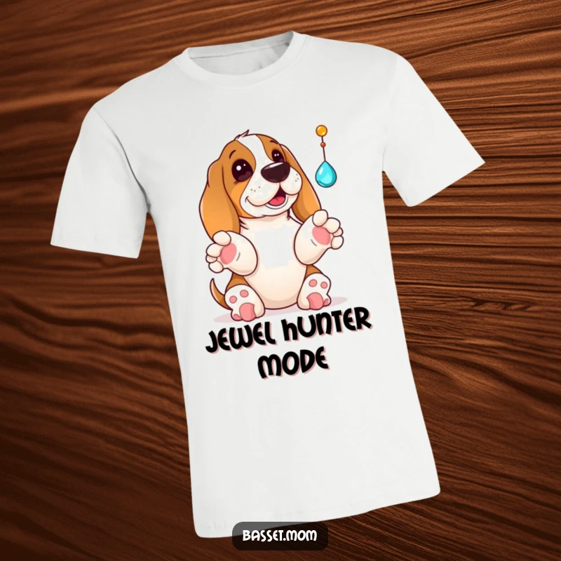 Funny Basset Hound t-shirt showing a dog with its paws up, playfully reaching for a dangling sparkling jewel, capturing a moment of excitement.